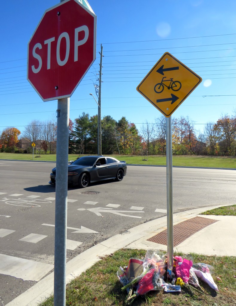 Motorists take wide turns pulling into Stevensgate Drive. The memorial is below. 