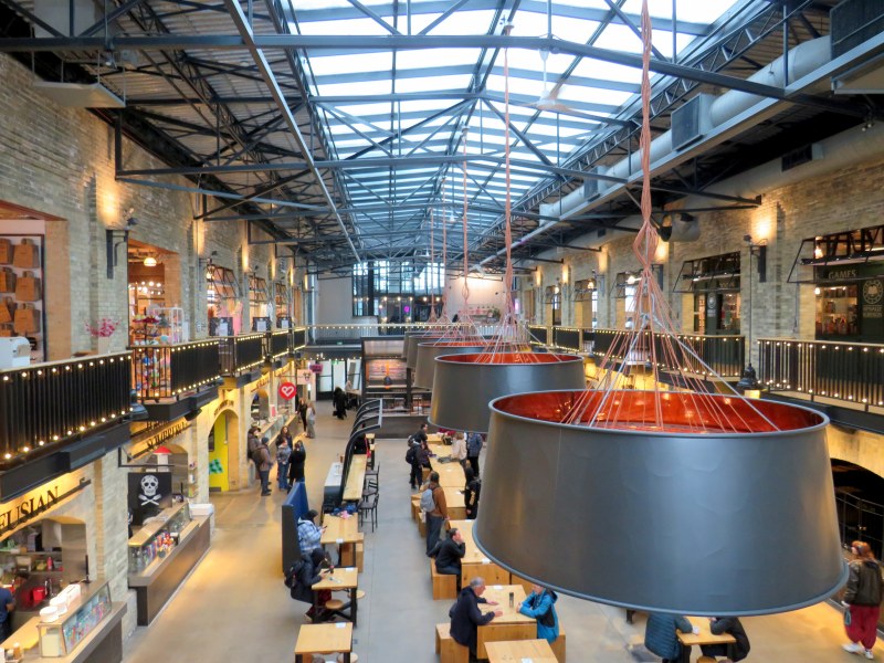 An old two-story brick industrial building with a great skylight, with tables and seating below